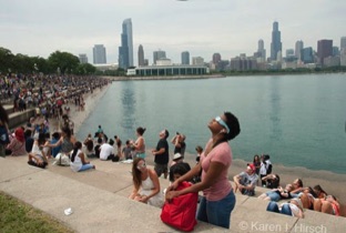 Woman looking up with eclipse glasses - Chicago skyline in background